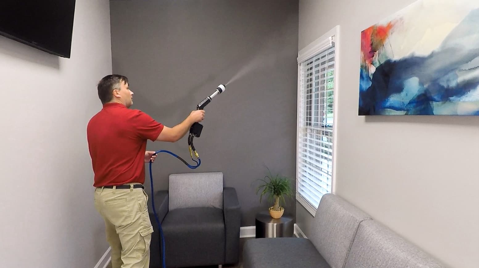 A picture of a man spraying germ control treatment in one room of a home.
