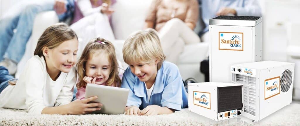 A picture of family in their living room with a few kids playing on a tablet. The SantaFe dehumidifiers are displayed in that room.